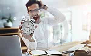 Panic mode. Portrait of a young businessman looking stressed out while holding a clock in an office.