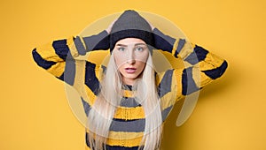 Panicking young woman stare to you, model wearing woolen cap and sweater,  on yellow background. Mistake. Bad news