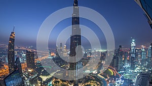 Paniramic skyline view of Dubai downtown with mall, fountains and Burj Khalifa aerial night to day timelapse