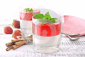 Panna cotta dessert with strawberry jelly on rustic wooden backg