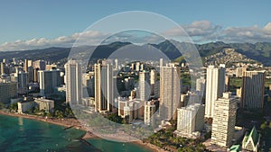 Panning aerial drone slowly flying over a colorful Honolulu Skyline while Sunset in Oahu, Hawaii with Waikiki Beach