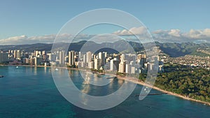 Panning aerial drone slowly flying over a colorful Honolulu Skyline while Sunset in Oahu, Hawaii with Waikiki Beach