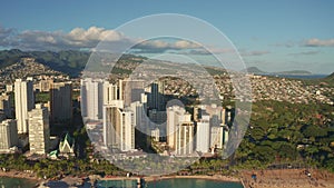 Panning aerial drone slowly flying over a colorful Honolulu Skyline while Sunset in Oahu, Hawaii with Waikiki Beach