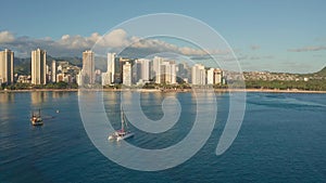 Panning aerial drone slowly flying over a colorful Honolulu Skyline while Sunset in Oahu, Hawaii with Waikiki Beach