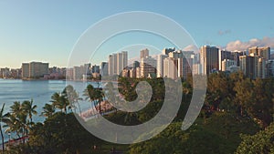 Panning aerial drone slowly flying over a colorful Honolulu Skyline while Sunset in Oahu, Hawaii with Waikiki Beach