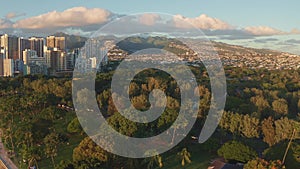 Panning aerial drone slowly flying over a colorful Honolulu Skyline while Sunset in Oahu, Hawaii with Waikiki Beach