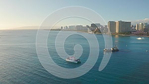 Panning aerial drone slowly flying over a colorful Honolulu Skyline while Sunset in Oahu, Hawaii with Waikiki Beach