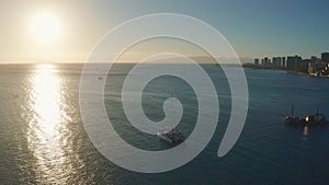 Panning aerial drone slowly flying over a colorful Honolulu Skyline while Sunset in Oahu, Hawaii with Waikiki Beach