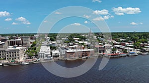 panning aerial footage along Cape Fear River with Cape Fear Memorial Bridge over the water, lush green trees and the Wilmington