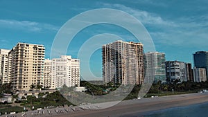 panning aerial footage of the coast of the Atlantic ocean with hotels and luxury condos in the city skyline at sunrise, palm trees