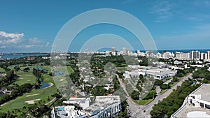 panning aerial footage of skyscrapers, hotels and apartments in the city skyline, cars on the street, Miami Beach Golf Club