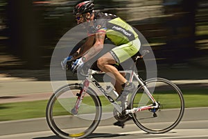 Panning of a cyclist riding bicycle in a sunny day, competing for Road Grand Prix event, a high-speed circuit race in