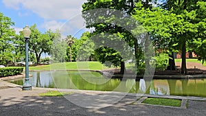 panning footage of a gorgeous spring landscape at Louis Armstrong Park with lush green trees and grass, a lake, blue sky