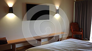 Panning right to left along wall with modern big TV-set in comfortable hotel room. Wide shot elegant technologies in