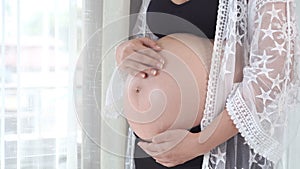 Panning shot of female hands pat pregnant belly