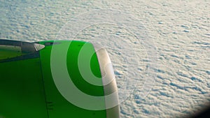 Panning shot of a green airplane engine flying over clouds