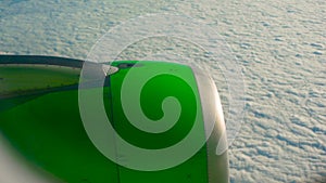 Panning shot of a green airplane engine flying over clouds