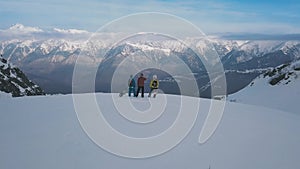 Panning shot group of active sports people with snowboarding and skiing standing on top of mountain