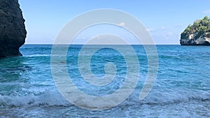 Panning shot revealing turquoise waves washing ashore onto white sand secluded beach.