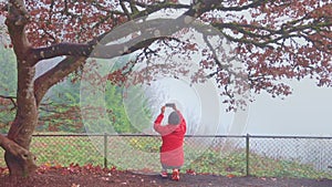 Panning shot of Senior man recording videos of autumn scene with a smartphone