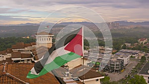 Panning to the left, the national flag of Palestine is waving above the building.
