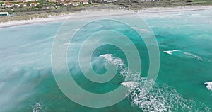 Panning up from waves in sea to chemical plant on coast. Aerial seascape