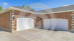 Pano Building with red brick wall gray roof and two white arched wooden garage doors