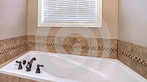 Pano Built in bathtub and shower stall inside bathroom of home with brown tiles