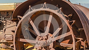 Pano Close up of the damaged wheels of an old vintage tractor against sunny blue sky