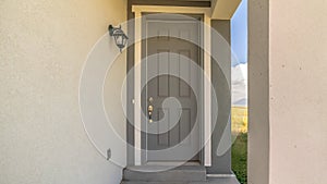 Pano Close up of home entrance with gray front door and lantern on the concrete wall