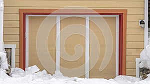 Pano Exterior of an attached single car garage of home with snowy driveway in winter