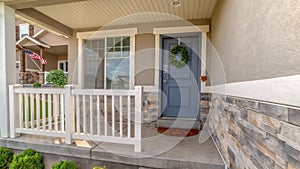 Pano frame Facade of a home with railing on the porch and front door decorated with wreath