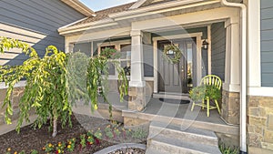 Pano frame Home with landscaped yard stairs porch and front door with sidelight and wreath