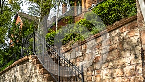 Pano frame Outdoor staircase against stone fence of home with red brick wall and balcony