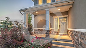 Pano Home entrance with pathway and stairs leading to porch and door with wreath