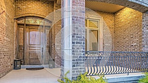 Pano Home facade with front porch brick wall and wooden door flanked by sidelights