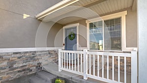 Pano Home facade with small porch and blue gray front door with green leafy wreath