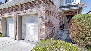 Pano House facade with two car garage and front door with wreath and sidelights