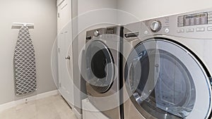 Pano Light gray laundry room with tiles, washer, dryer and storage room
