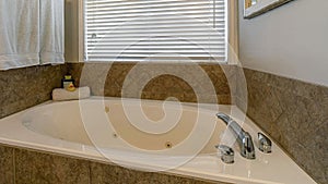 Pano Round built in bathtub against window with blinds of bathroom of a house