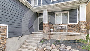 Pano Stairs going up the porch of home with gray front door and window at the facade