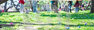 Panorama abundant of colorful Easter eggs on green grass field with blurry diverse people kids parents waiting behind vinyl tape