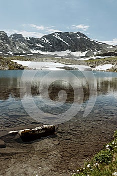 Panorama of alpine lake with melting ice and mountains