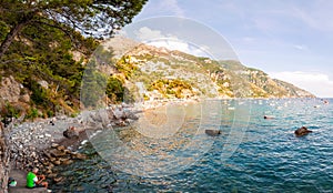 Panorama of amazing Positano cityscape on rocky landscape, people resting, swimming, fishing on the beach, boats are coming and