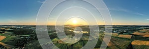 Panorama of amazing rural sunset; aerial view of green fields and houses