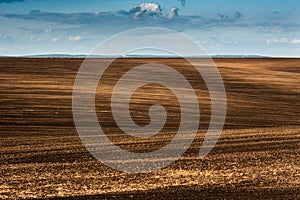 Panorama of arable land over clouds sky