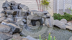 Panorama Artificial stone cascade waterfall in backyard on a sunny day