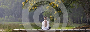 Panorama back view of woman relaxingly practicing meditation in the public park to attain happiness from inner peace wisdom with