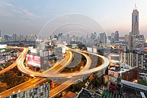 Panorama of Bangkok at dusk with skyscrapers in background and busy traffic on elevated expressways & circular interchanges photo