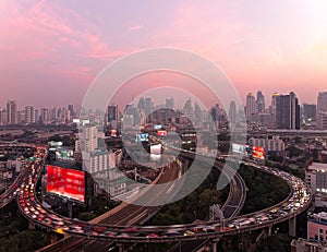 Panorama of Bangkok at dusk with skyscrapers in background & heavy traffic on elevated expressways & circular interchanges photo